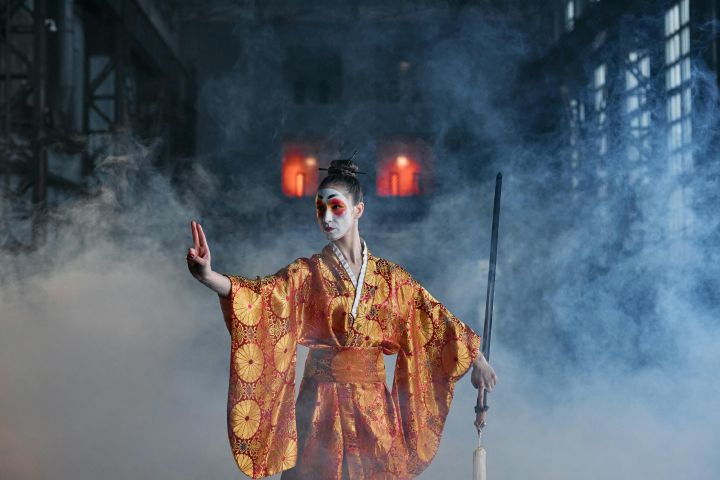 Geisha warrior in traditional kimono holds a sword in a dramatic, smoky ambiance.