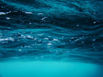 Serene underwater view of sea surface with vibrant turquoise and blue waves.