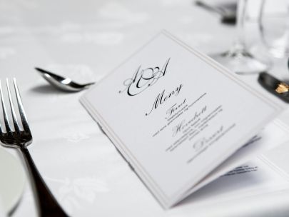 Close-up of a refined dining table with menu and silverware, showcasing elegance in a formal restaurant setting.