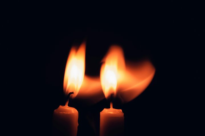 Two candles burning brightly against a dark background, creating a warm glow.