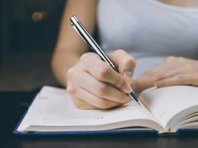 Woman writing in a notebook, capturing a moment of focused concentration.