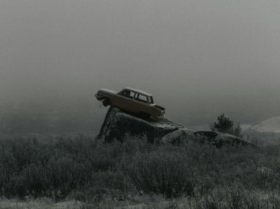 Mysterious abandoned car perched on a rock amid a foggy landscape in Altai, Russia.