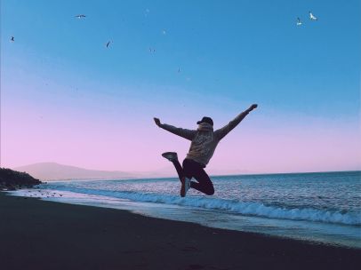 A man jumping on a beach under a crescent moon, symbolizing freedom and joy.