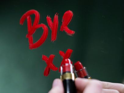 Handwriting 'bye' on a mirror with red lipstick, evoking themes of farewell and emotion.